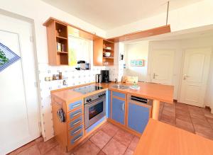 a kitchen with blue cabinets and a wooden counter top at Ferienwohnung Soling - ideal für Paare, mit Wasserblick in Alt Reddevitz +9 photos