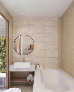 Un baño con bañera, lavabo y espejo. en Gaia Eco Suites, en Phu Quoc