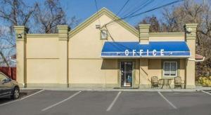 um prédio com toldo azul e cadeiras em um estacionamento em Rodeway Inn Allentown South em Allentown