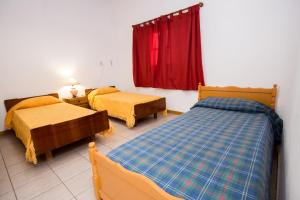 1 dormitorio con 2 camas y cortina roja en Casa Guaymare en Mendoza