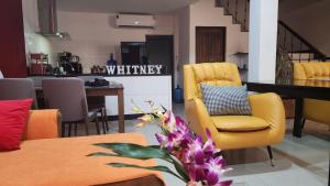 a living room with a yellow chair and a table at Villa Whitney in Lamai