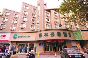 济南GreenTree Inn Jinan Quancheng Hotel的街道上的人在前面的建筑物