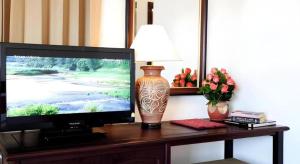 a television on a table with a lamp and a vase at Lao Golden Hotel in Ban That-Louang