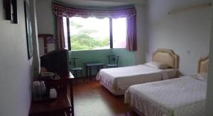 um quarto de hotel com duas camas e uma janela em Hotel Hung Hung em Kampung Boyan