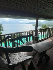 a bench on a porch with a view of the ocean at Waddy Inn and Leisure Farm in Taytay