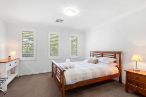 Callala BeachにあるSunkissed Manor - Swimming Pool - 3 Mins to Beachのベッドと机と窓のある寝室 +22枚の写真