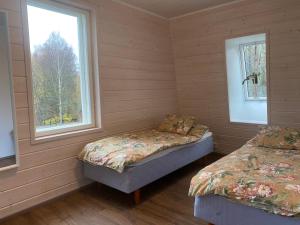 two beds in a room with two windows at Idyllic Charm- with a moat! in Kangasala