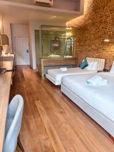 een slaapkamer met twee bedden en een bakstenen muur bij Loke Thye Kee Heritage Hotel in George Town