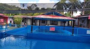 un edificio con una valla azul al lado de un cuerpo de agua en OYO Home 90554 Norfa Camp House, en Kampong Tanah Baharu