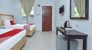 a hotel room with two beds and a desk with a phone at Collection O 90622 Sehijau @ Cenang in Pantai Cenang
