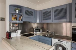 Una cocina con armarios azules y lavadora. en Lisbon Apartments by Propr, en Cascais