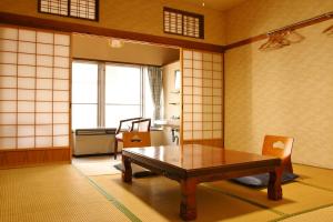 Habitación con mesa, sillas y ventana en Takasagoya Ryokan en Zao Onsen