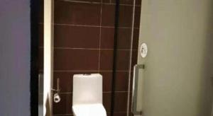 a bathroom with a toilet and a tiled wall at IU Hotels·Anshun Nanma Square in Anshun