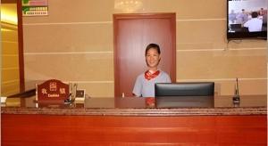 嘉兴GreenTree Inn Jiaxing Zhongan Business Hotel的一位男士在办公桌前戴着领结