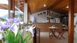 a kitchen with a table and chairs and purple flowers at Pousada Encontro das Águas in Trindade