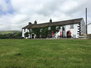 a house with a grass field in front of it at The Street Head Inn in West Burton