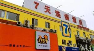 a yellow and orange building with a sign on it at 7 Days Inn Qinhuangdao Changjiang Road Chinese Medicine Hospital Branch in Qinhuangdao