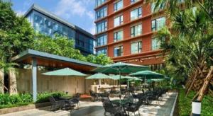 Un patio con sillas y sombrillas frente a un edificio. en Four Points by Sheraton Haikou International Airport, en Haikou
