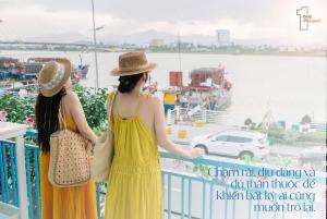 zwei Frauen stehen auf einem Balkon mit Blick auf das Wasser in der Unterkunft Santori Homestay Nhật Lệ in Dong Hoi