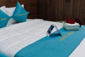 ein Bett mit blau-weißen Laken und eine Schale mit roten Rosen in der Unterkunft Santori Homestay Nhật Lệ in Dong Hoi