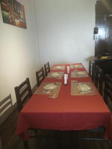 Strand Hotel, Colaba في مومباي: طاولة طعام مع طاولة قماش وكراسي حمراء