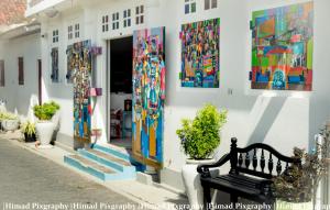 a bench in front of a building with paintings at Antic Guesthouse - Galle Fort in Galle