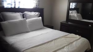 a bed with white sheets and pillows in front of a mirror at Namasiku's Self Catering in Katima Mulilo