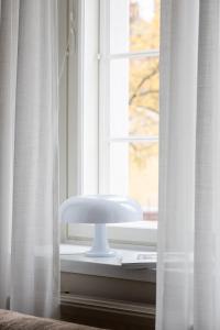a white chair sitting in a window with curtains at Stylish & Cozy 1BR Apt in Historical Neighborhood in Tampere