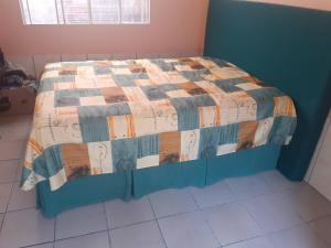 a bed with a quilt on it in a room at Quarto em casa com moradores in São José