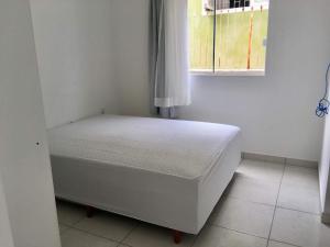 a small bed in a room with a window at Quarto em casa com moradores in São José