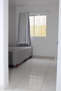 a white room with a bed with a window at Quarto em casa com moradores in São José