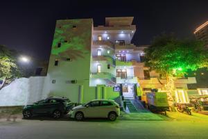 twee auto's geparkeerd voor een gebouw 's nachts bij Hotel Warm Welcome Inn 51 in Noida