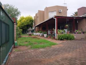 a building with plants in pots on a brick driveway at Lily Guesthouse in Bloemfontein +16 photos