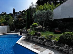 een zwembad in een tuin met een stenen muur bij Maison V in Ventabren