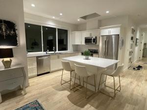 een keuken met een witte tafel en een koelkast bij Modern, Cheerful 2 Bdrm Ohana Vacation Cottage in Kelowna