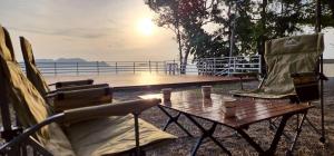 Ban Muang Thaeoภูผาหน้าเล PhuPha-NaLay Cafe'n Camping的甲板上配有两把椅子和一张桌子,享有日落美景