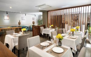 ein Restaurant mit weißen Tischen und Stühlen und gelben Blumen in der Unterkunft Dusit Hotel Siem Reap in Siem Reap