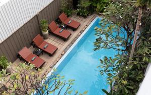 einen Blick über einen Pool mit Liegestühlen und einem Pool in der Unterkunft Dusit Hotel Siem Reap in Siem Reap