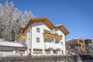een huis in de sneeuw met een houten hek bij Chalet Milandora in La Villa