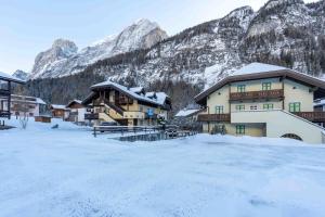 a building in the snow with mountains in the background at Cesa Vivi in Canazei
