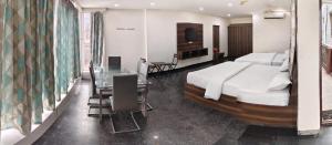 ein Schlafzimmer mit einem großen Bett, einem Tisch und einem Schreibtisch in der Unterkunft 7Hills Residency in Anantapur