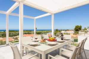 a dining room with a table and chairs and a view of the ocean at Villa Dolce Vita by Escape Home in Son Bou