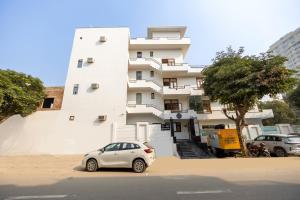 a white building with a car parked in front of it at Hotel Warm Welcome Inn Noida Sector 51 in Noida