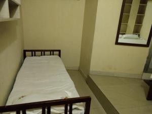 a small bedroom with a bed and a mirror at JS Homestay in Nāgercoil
