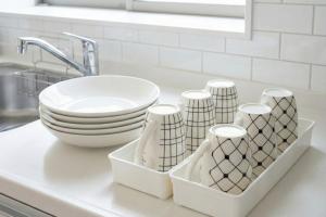 a kitchen counter with dishes and a bowl and a sink at Riverside Mizukiリバーサイドミズキ in Uruma