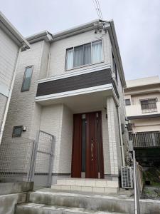 a house with a brown door and stairs in front at Riverside Mizukiリバーサイドミズキ in Uruma