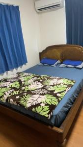 a bed in a room with a blue curtain and a bed with a bedskirts at Riverside Mizukiリバーサイドミズキ in Uruma
