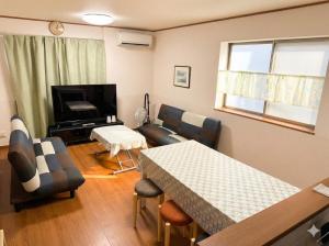 a living room with a table and a couch and a television at Riverside Mizukiリバーサイドミズキ in Uruma