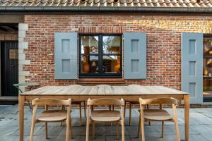 ブランケンベルヘにあるMaison 42のレンガの壁の前に木製のテーブルと椅子