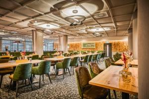 a restaurant with wooden tables and green chairs at Sauerland Stern Hotel in Willingen